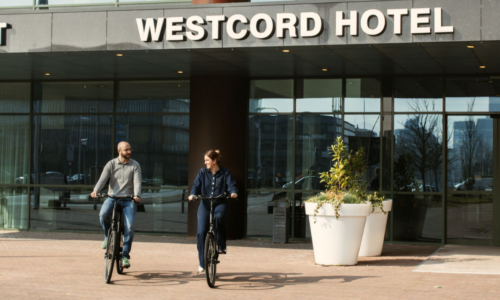 Man en Vrouw op fiets voor het WTC Hotel