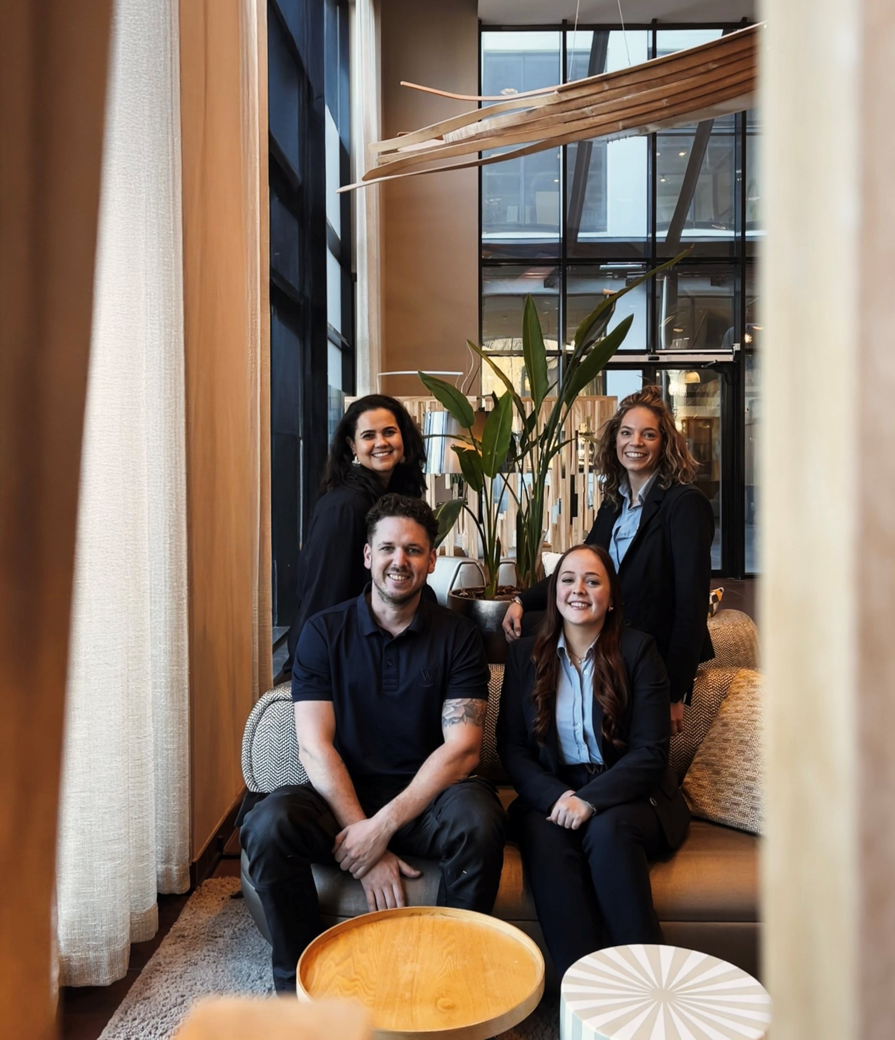 Vier medewerkers van WestCord Hotel Eindhoven in de lobby met een plant op de achtergrond.